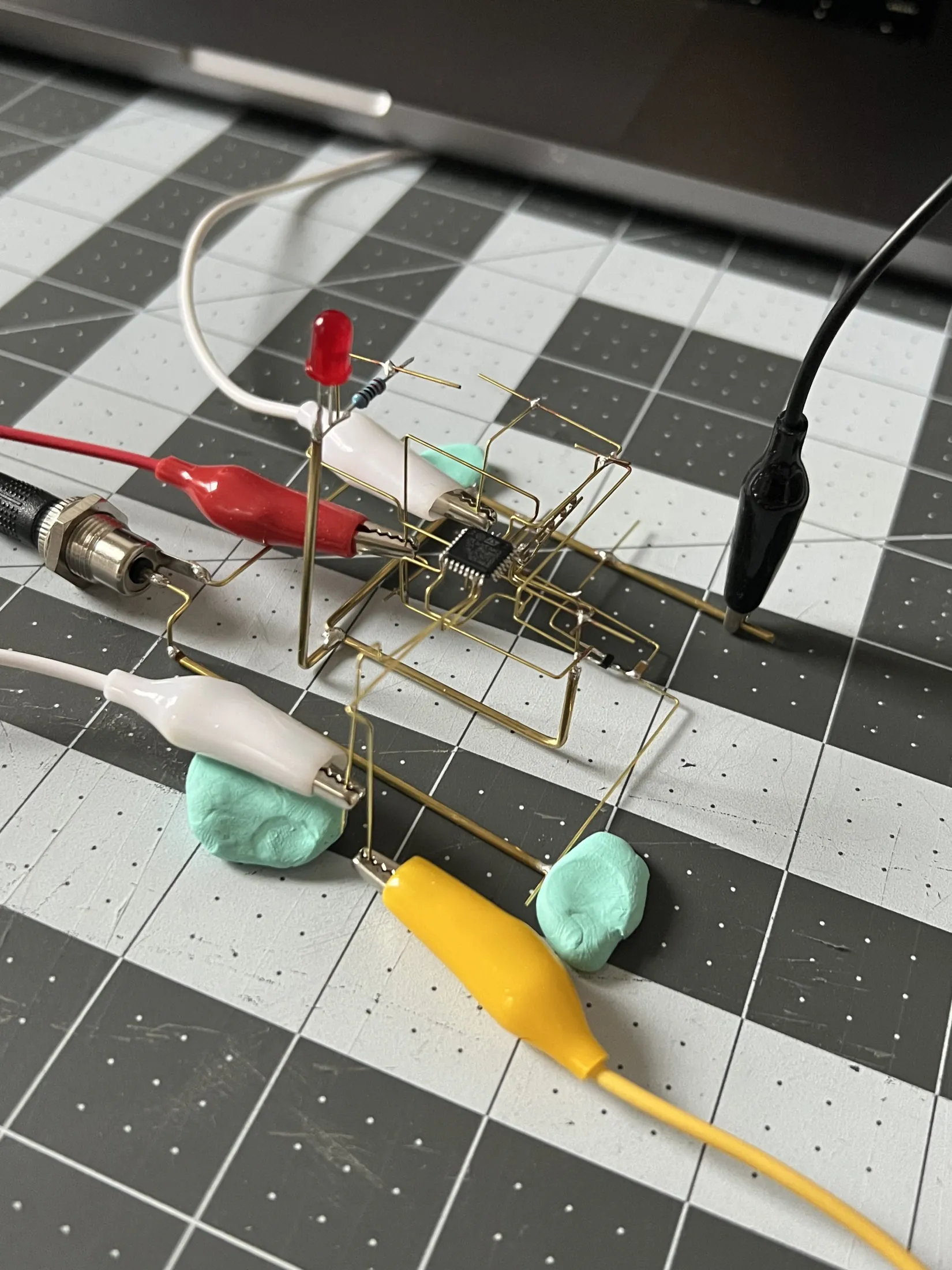 Alligator clips attached to the clock's brass rods to program the STM32, the frame held in place with putty