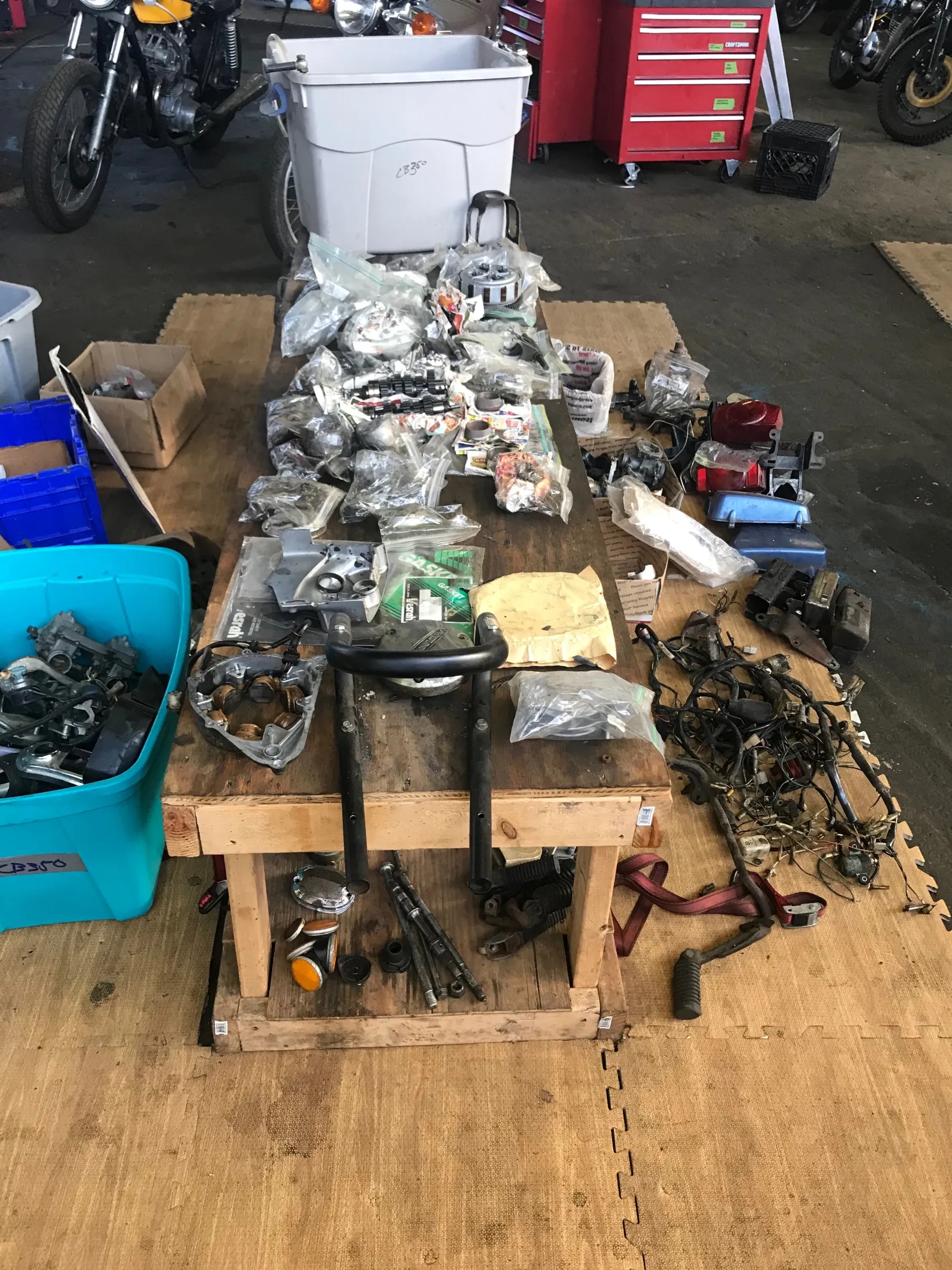 Workbench covered in bagged, oil-soaked parts from the disassembled bike