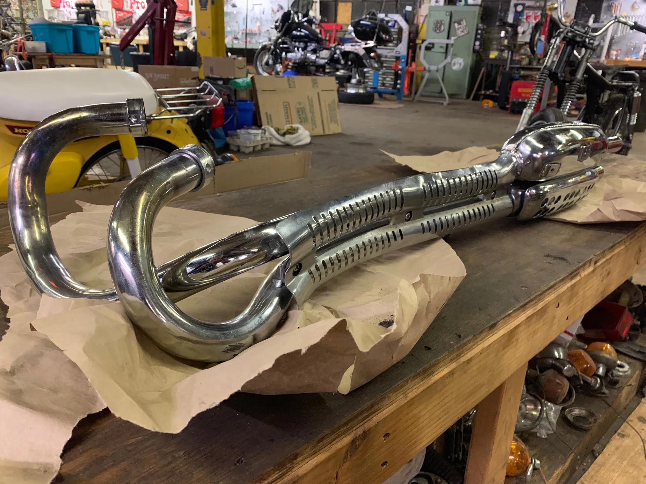 Pair of chrome scrambler exhaust pipes on a workbench