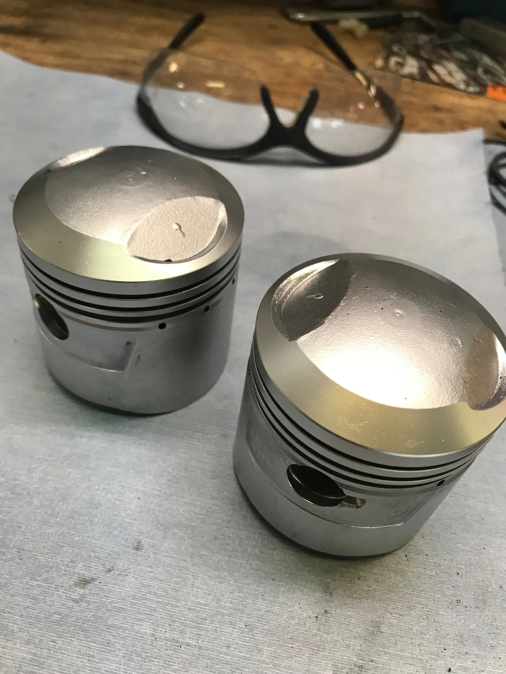 The same two pistons after vapor blasting, clean bare aluminum