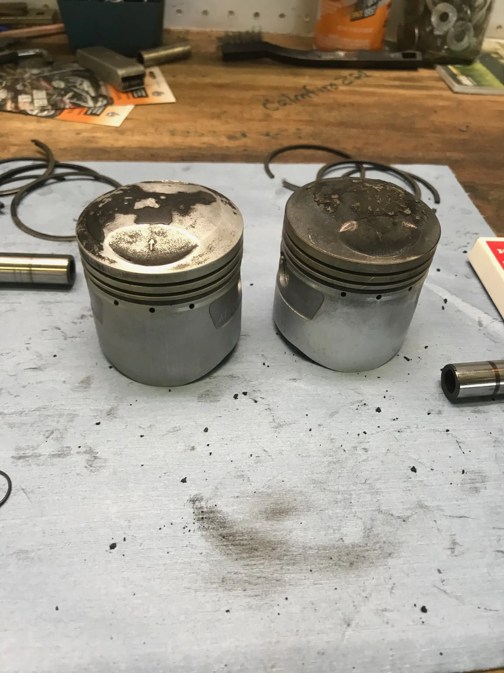 Two pistons caked in decades of carbon buildup